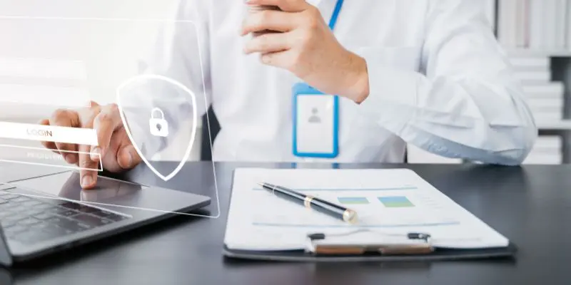 Person sitting at desk with clipboard and laptop