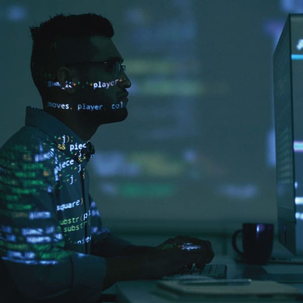 Businessman working at a large computer screen with code projected across the room