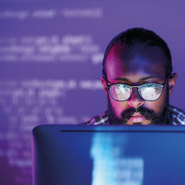 Man working on computer with coding projected in the background