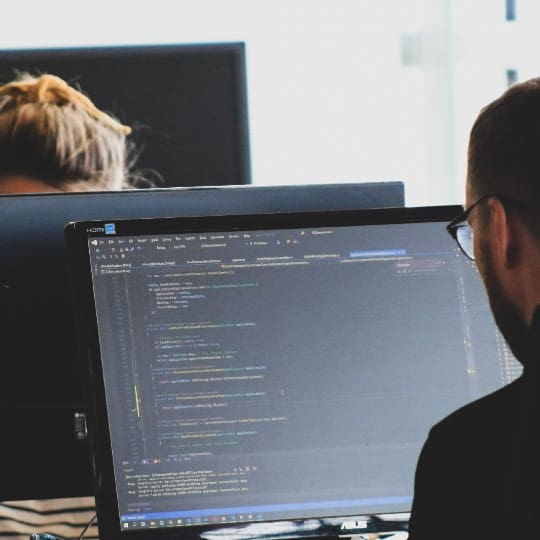 Over the shoulder view of a man coding on a desktop computer