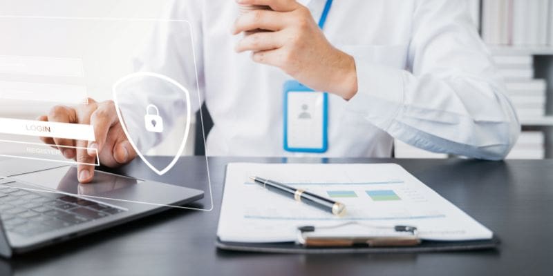 Person sitting at desk with clipboard and laptop